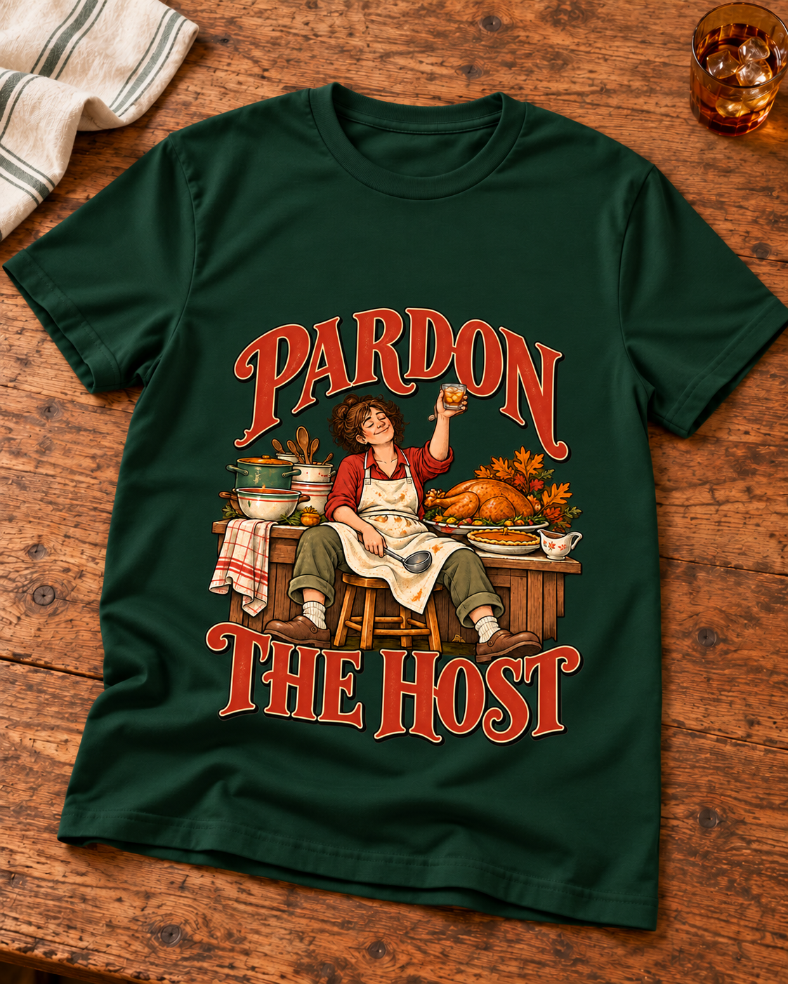 Pardon the Host raised-drink design on a Forest Green T-shirt, styled on warm kitchen wood