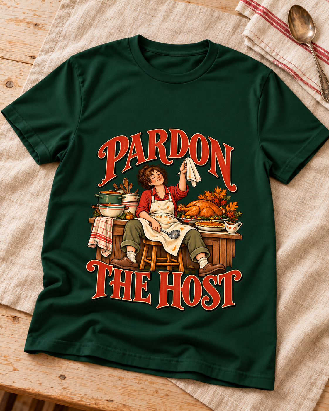Pardon the Host original towel design on a Forest Green T-shirt, styled on warm linen