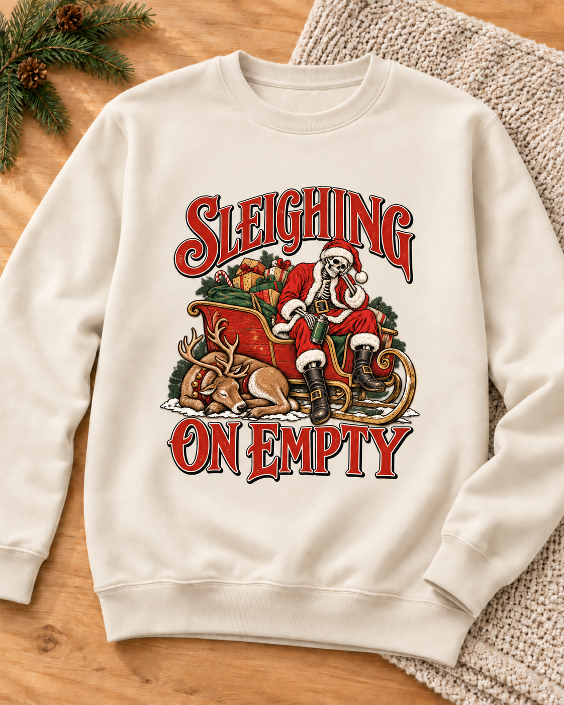 Sleighing on Empty design on a Pigment Ivory crewneck sweatshirt, styled with warm wood and a knit throw